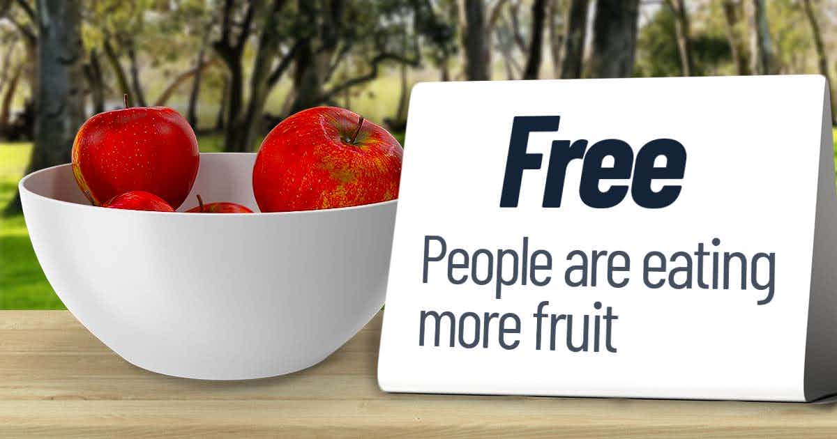 Bowl of apples on a public table with sign that says "Free - people are eating more fruit"